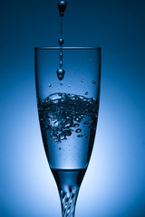 glass of water with splash on blue background