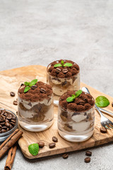 Classic tiramisu dessert in a glass on dark concrete background