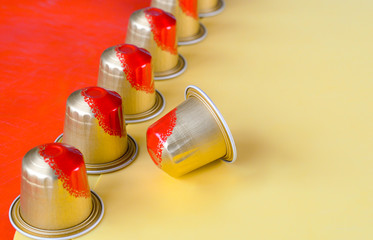 Orange and gold colour coffee capsules on an orange and yellow background