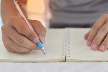 Male hand writing on a notebook with pen.