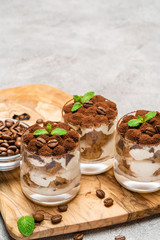 Classic tiramisu dessert in a glass on dark concrete background