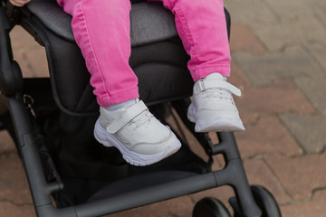 Little girl sitting in a baby carriage on the street