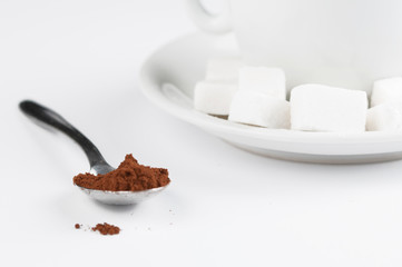 White coffee cup with sugar cubes  and metal spoon isolated on white background.