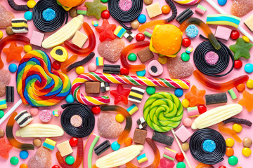 lollipops and candies on pink like background, top view