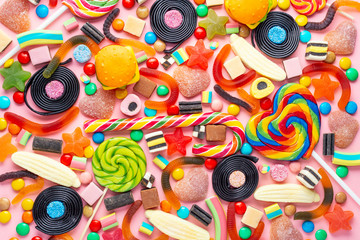 assortment of colourful lollipops, fruit bonbon and candies on pink like background