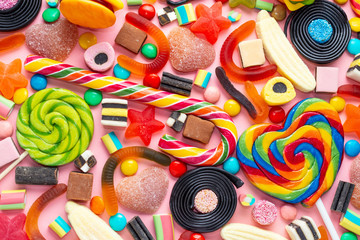 top view of assortment colourful lollipops and candies on pink like background,  close up