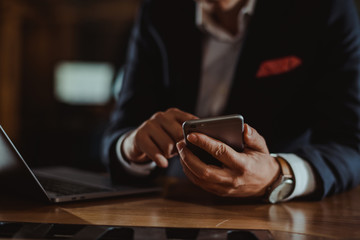 Close-up of hands using phone and laptop