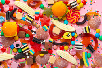 Obraz na płótnie Canvas candies with jelly and sprinkles colorful array of different childs sweets and treats over pink like festive background