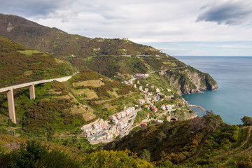 Fototapeta na wymiar Manarola / Italy - April 27 2019: View of the coastal city of Riomaggiore (Cinque Terre) from the hiking trails above the city.
