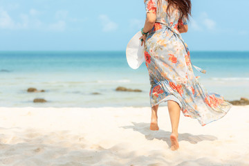 Lifestyle woman wearing fashion  dress summer running on the sandy ocean beach. Happy woman enjoy and relax vacation. Lifestyle and Travel Concept