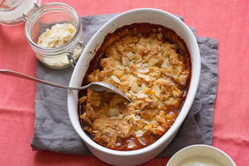 Overhead image of plum cobbler with almond flakes and cream