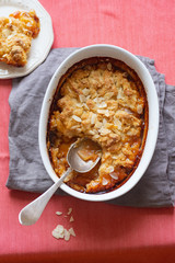 Overhead image of plum cobbler with almond flakes and cream