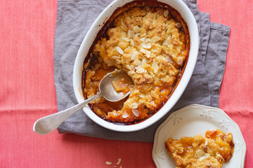 Overhead image of plum cobbler with almond flakes and cream