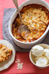 Overhead image of plum cobbler with almond flakes and cream