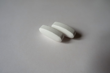 Close view of 2 big white oblong caplets of calcium citrate