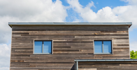 Modernes Wohnhaus mit Fassade aus Holz und Flachdach aus Blech - Modern residential house with wooden façade and flat roof made of sheet metal