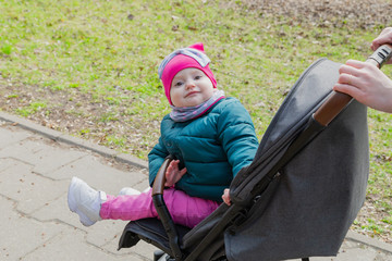 Little girl sitting in a baby carriage on the street