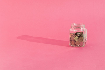 russian coins in transparent glass jar on a pink background