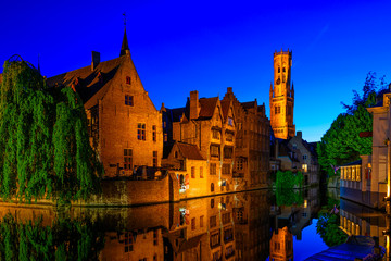 Fototapeta premium Klasyczny widok na historyczne centrum miasta z kanałem w Brugii, prowincja Flandria Zachodnia, Belgia. Nocna panorama Brugii.