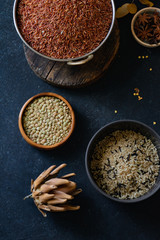 Various types of rice and grains with spices on blue background. Brown rice and mixed wild rice.