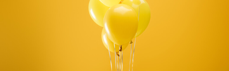 festive minimalistic decorative balloons on yellow background, panoramic shot