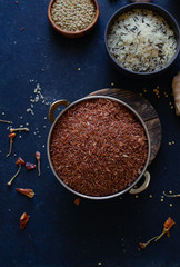 Various types of rice and grains with spices on blue background. Brown rice and mixed wild rice.