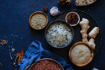 Various types of rice and grains with spices on blue background. Brown rice and mixed wild rice.