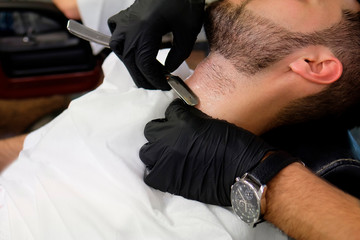 A barber shaves his client's beard in the traditional way. straight razor