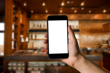 Hand holding white mobile phone with blank white screen  in cafe.