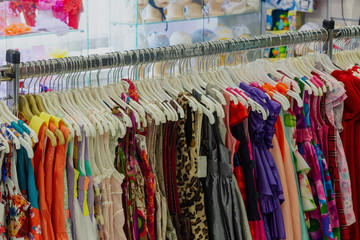 Beautiful colorful clothes in a store on hangers.