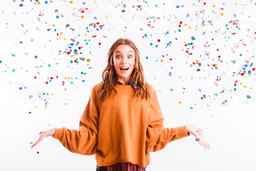 Obraz premium Cute teen girl on a light background throws color candy. Party concept.