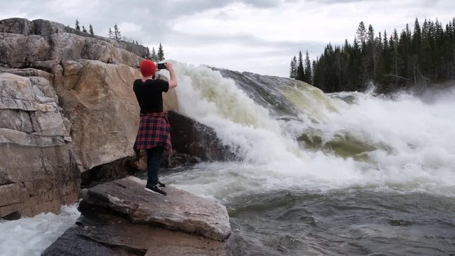 tourist stands under a waterfall, takes pictures how does water flow