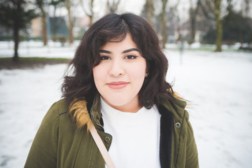 portrait of young brunette woman standing outdoor and looking camera