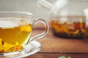 glass teapot with cup of black tea on wooden table