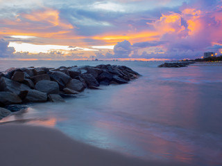 Many stones that are stacked in the sea and on a colorful sky background, sunset