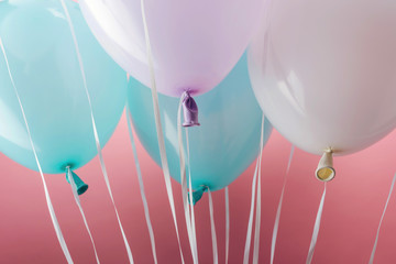 close up view of blue, white and purple balloons on pink background