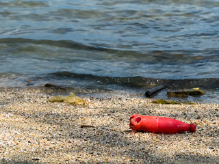 Red soda bottles that were left by tourists on the beach,.Plastic waste