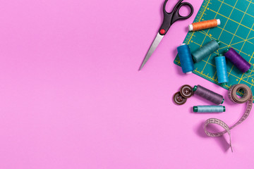 Sewing accessories on a plastic pink background. Top view, flatlay