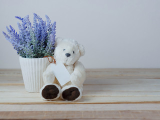 Purple lavender pots and cute teddy bears with blank paper tag  and placed on a wooden table for the background