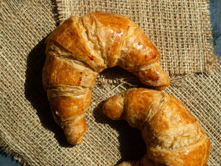 Fresh butter croissants on a mat that is placed on a dark gray wood table