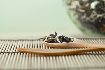 Brown rice in a wooden spoon placed on a light brown wood table