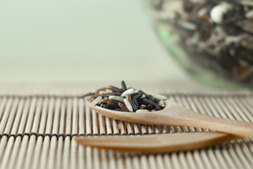 Brown rice in a wooden spoon placed on a light brown wood table