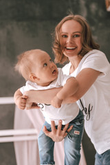 Young mother woman with a son, the small child shook his hands in the nursery