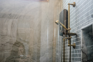 Wall-mount unlacquered brass rail and rain shower head, gray bathroom tile. Loft interior, minimalism concept, copy space