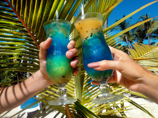Healthy drink on a Caribbean beach. Pineapple and coconut handheld on the beach among palm trees...