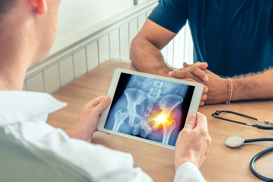 Doctor holding a digital tablet with x-ray of hips of the patient. Pain on the right hip