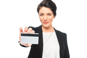 selective focus of smiling mixed race businesswoman showing credit card isolated on white