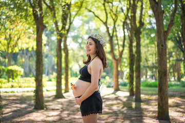 Happy pregnant woman making heart gesture over green natural background