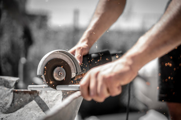 Handwerker schneidet mit dem Winkelschleifer und der Flex Gewindestange auf der Baustelle und die...