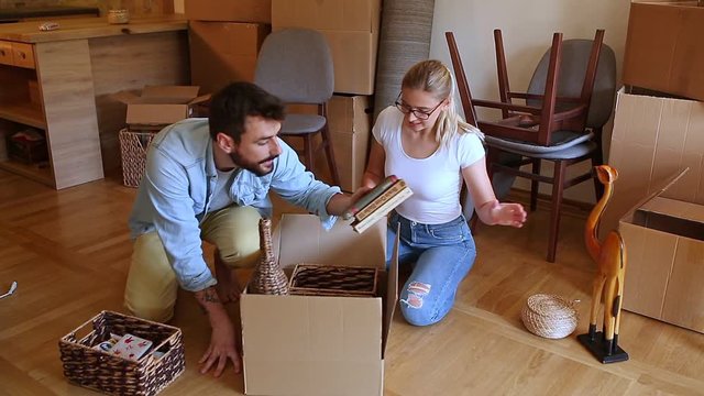 Young couple unpacking cardboard boxes at new home.Moving house concept.